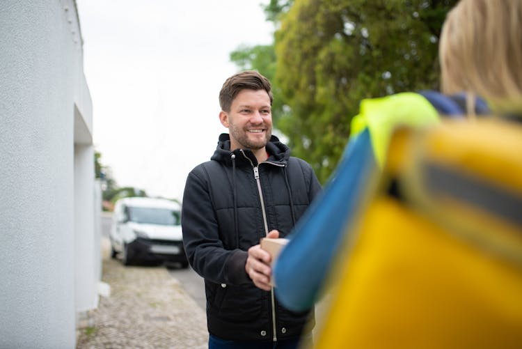 A Happy Man In A Black Jacket Receiving A Package