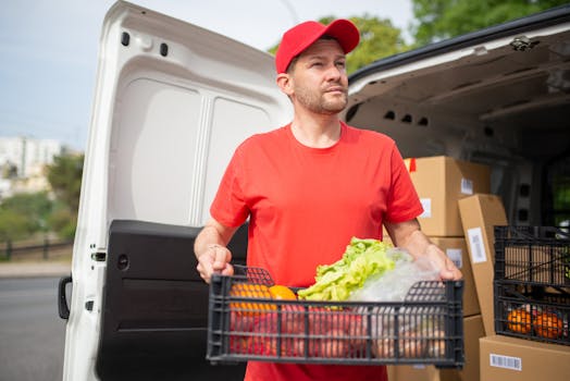 Man delivering groceries from van in sunny Portugal, showcasing fresh produce.