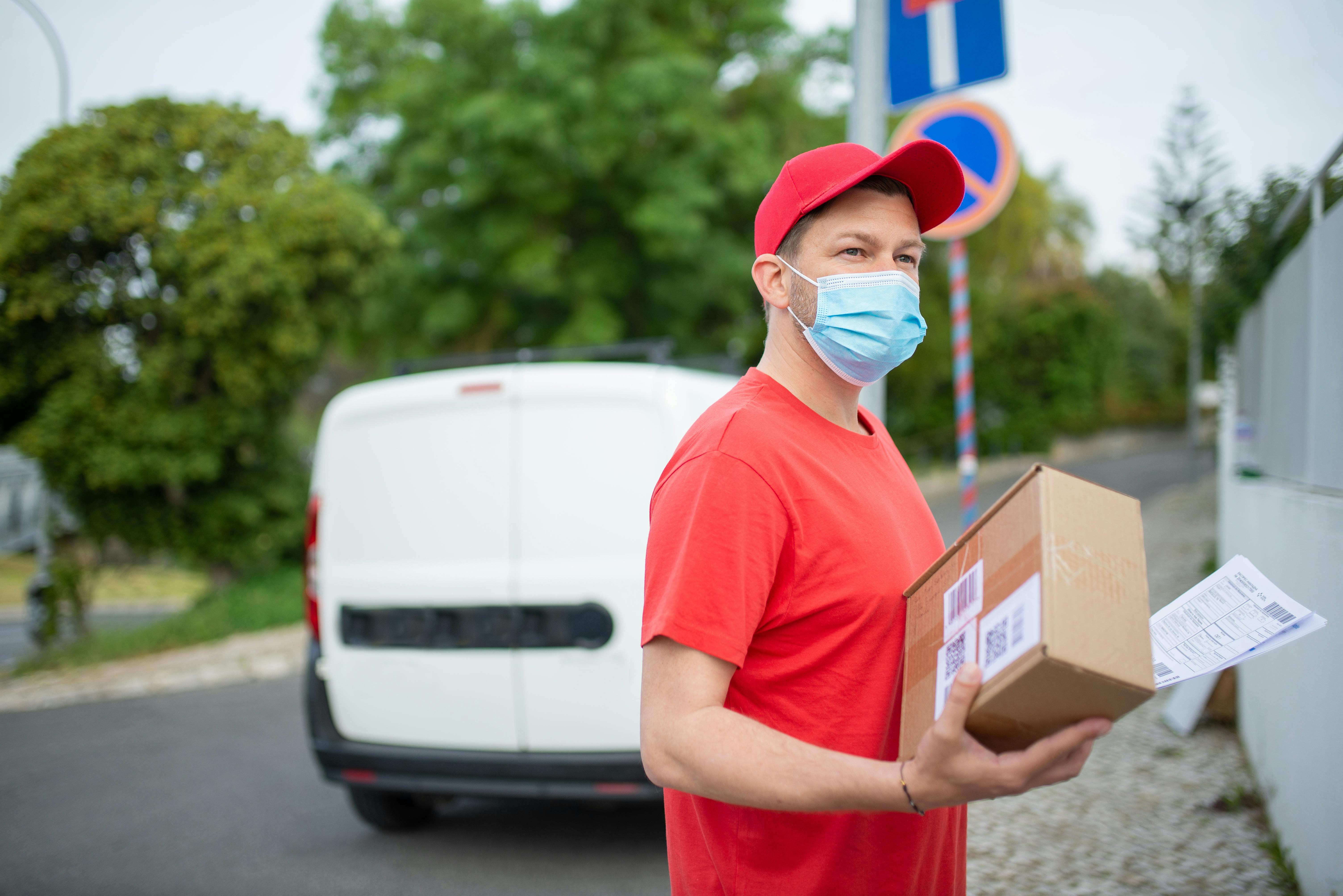 a man wearing face mask holding a parcel