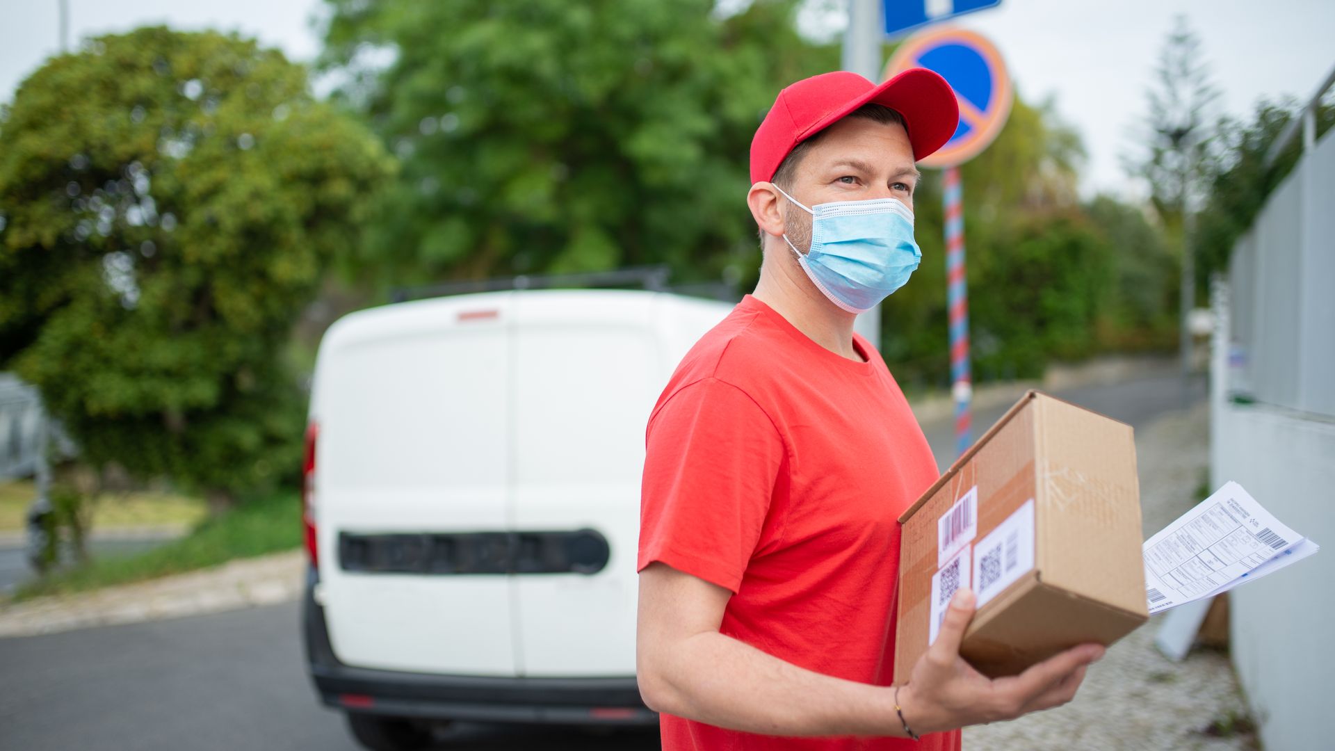 Modafinil Delivery to Canada: Comprehensive Guide Masked delivery person holding a package outdoors. COVID-19 safety measures in action — modafinil delivery to canada