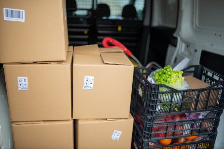 Brown Cardboard Boxes Beside The Plastic Crates With Farm Produce