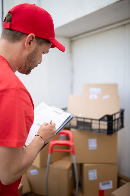 Man in Red T-shirt Holding White Printer Paper