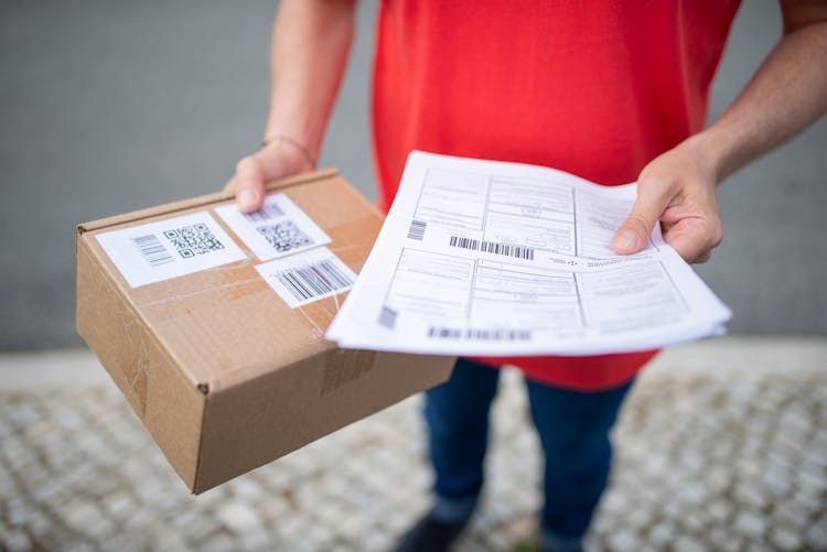 Person Holding A Papers And Box