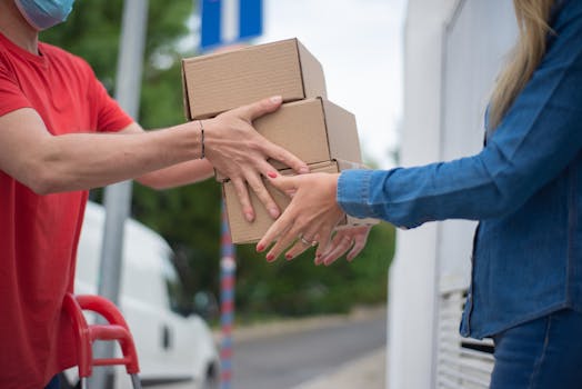 Hands exchanging cardboard boxes during an outdoor delivery scene.