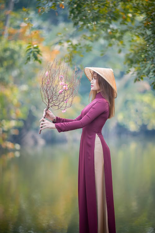 Free A Woman Looking at the Stem of Flowers she is Holding Stock Photo