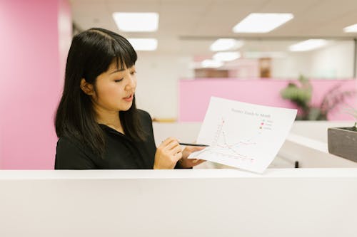Free A Woman in the Office Holding a Document with with Graphs Stock Photo