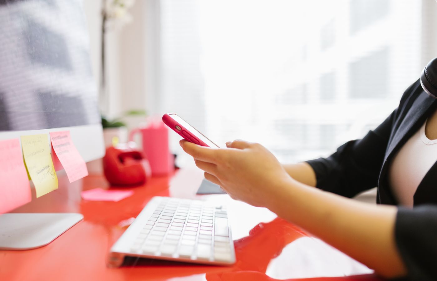 Professional checking mobile phone at modern office workstation.