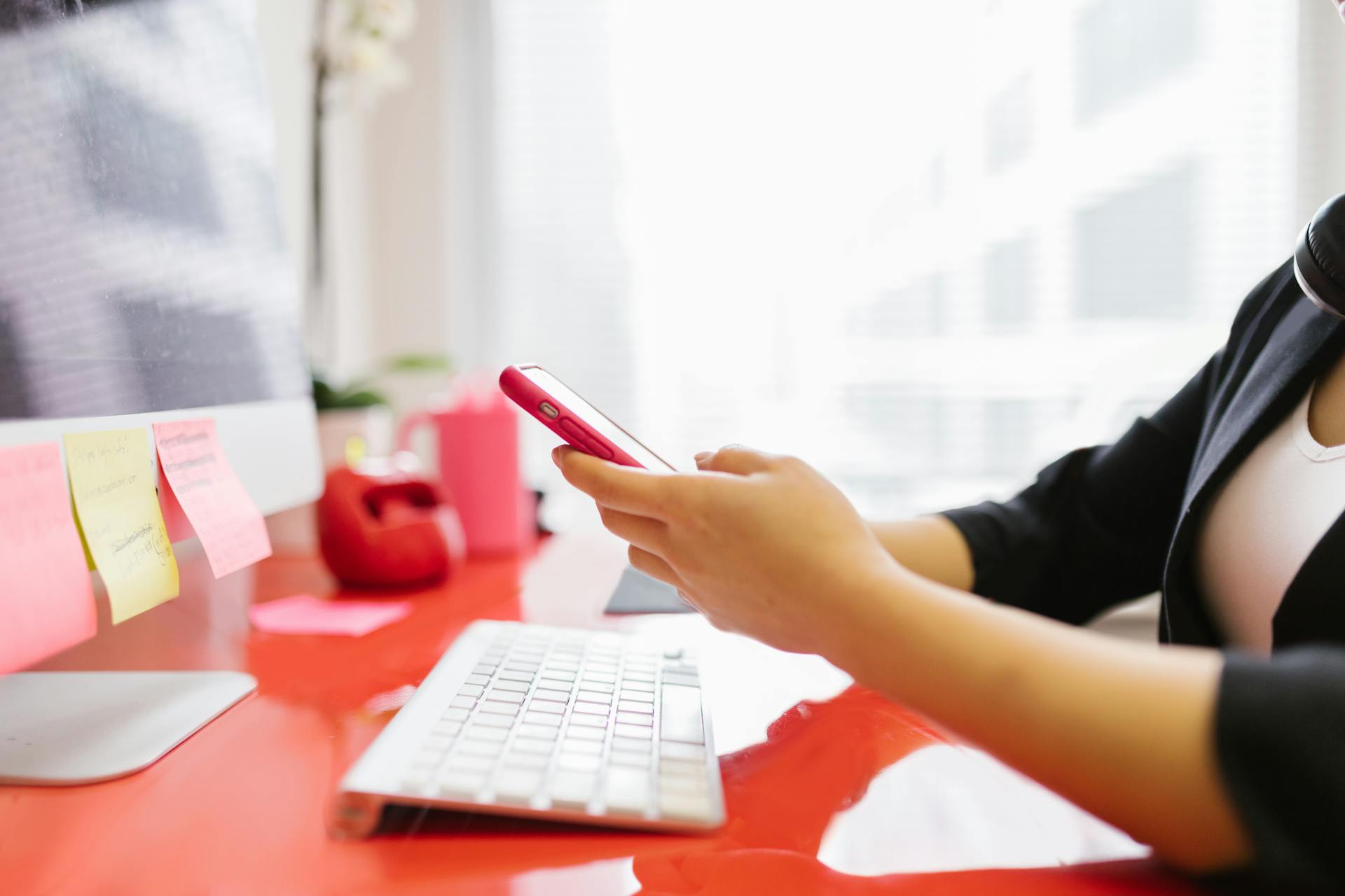 Professional checking mobile phone at modern office workstation.