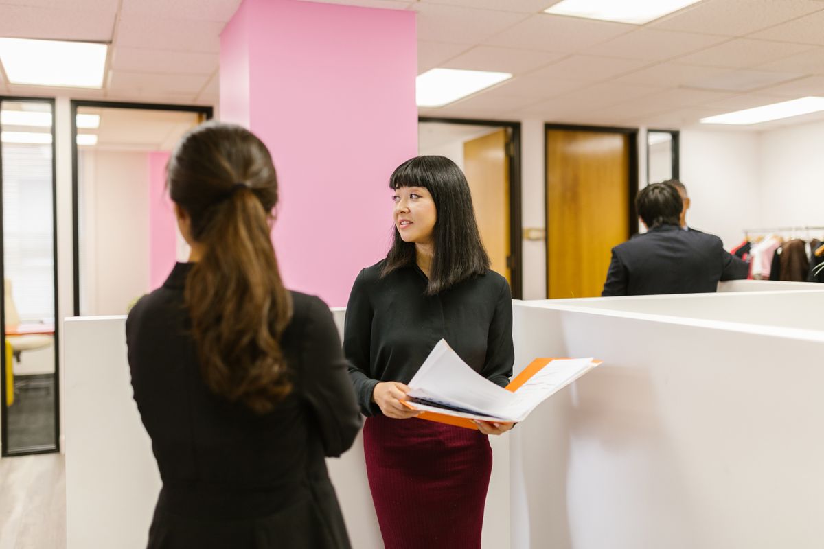 Two colleagues in business attire discussing documents in bright office