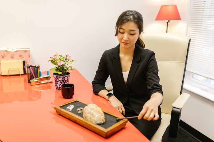 A Woman Using A Mini Zen Garden At The Office