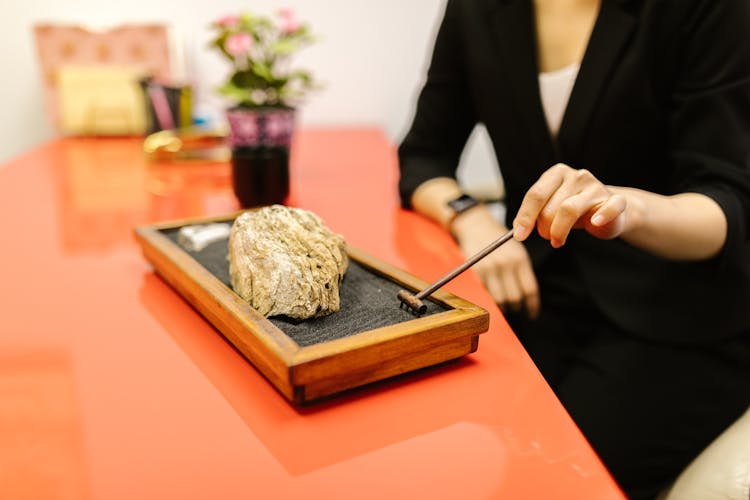 A Person Raking Sand In A Mini Zen Garden