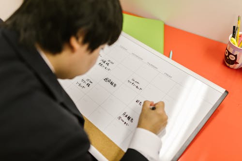A Man in Black Suit Writing on the Calendar