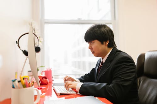 A Man Using a Desktop Computer at an Office