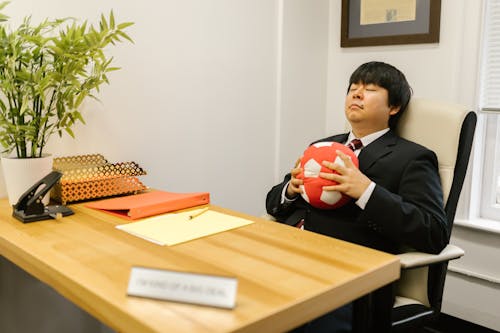 Free A Man in the Office Chair Holding a Pillow While His Eyes Closed Stock Photo