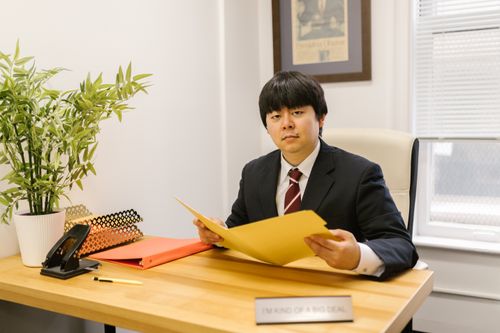Free Asian businessman holding a folder in a modern office setting. Stock Photo