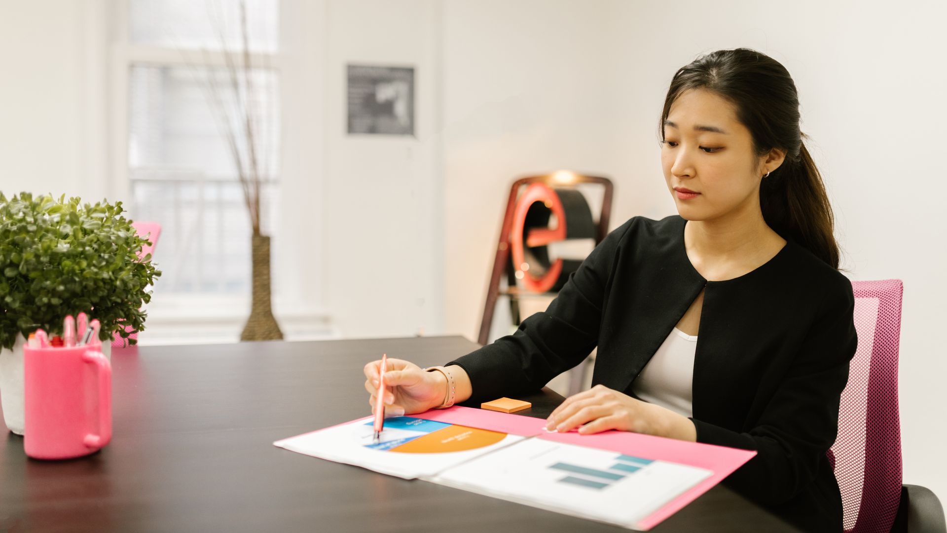 Woman in business attire analyzing documents at her office desk with reports and graphs — modvigil 200mg review