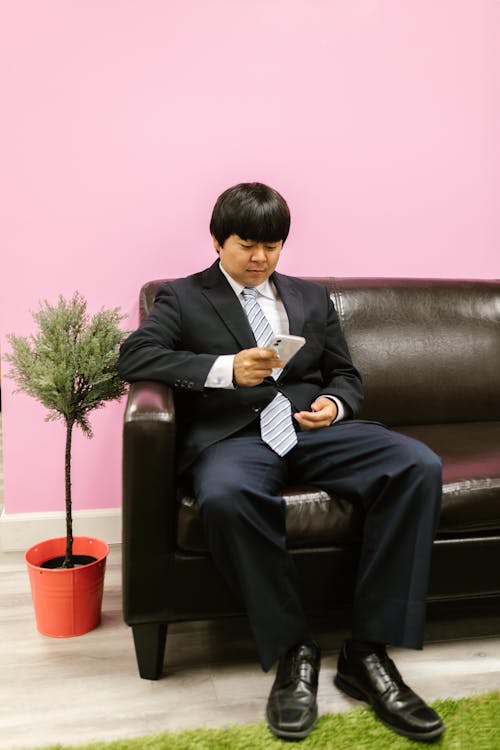 Free A Man is Using His Cellphone While Sitting Stock Photo