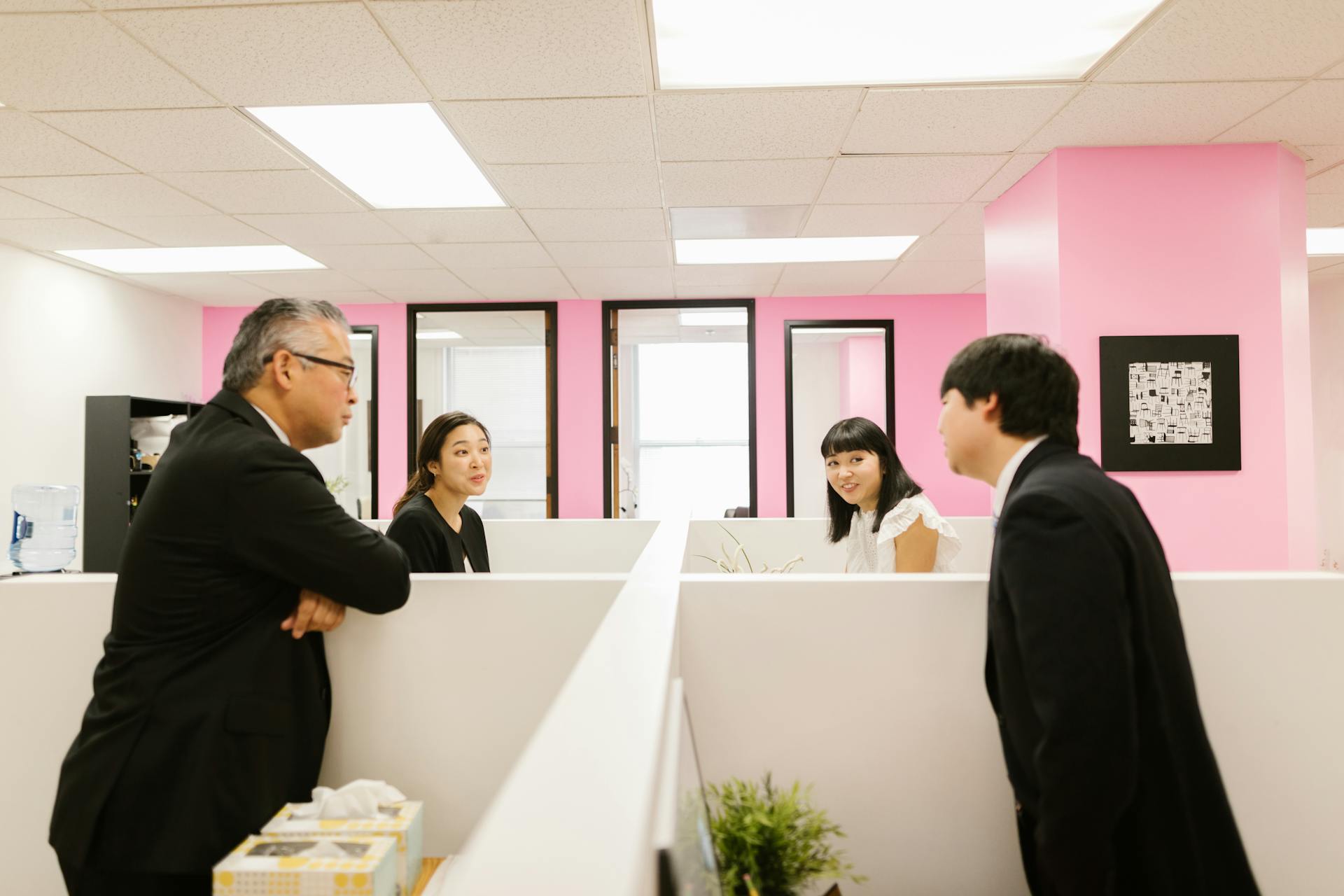 A group of Asian colleagues engaged in a lively discussion in a modern office setting.