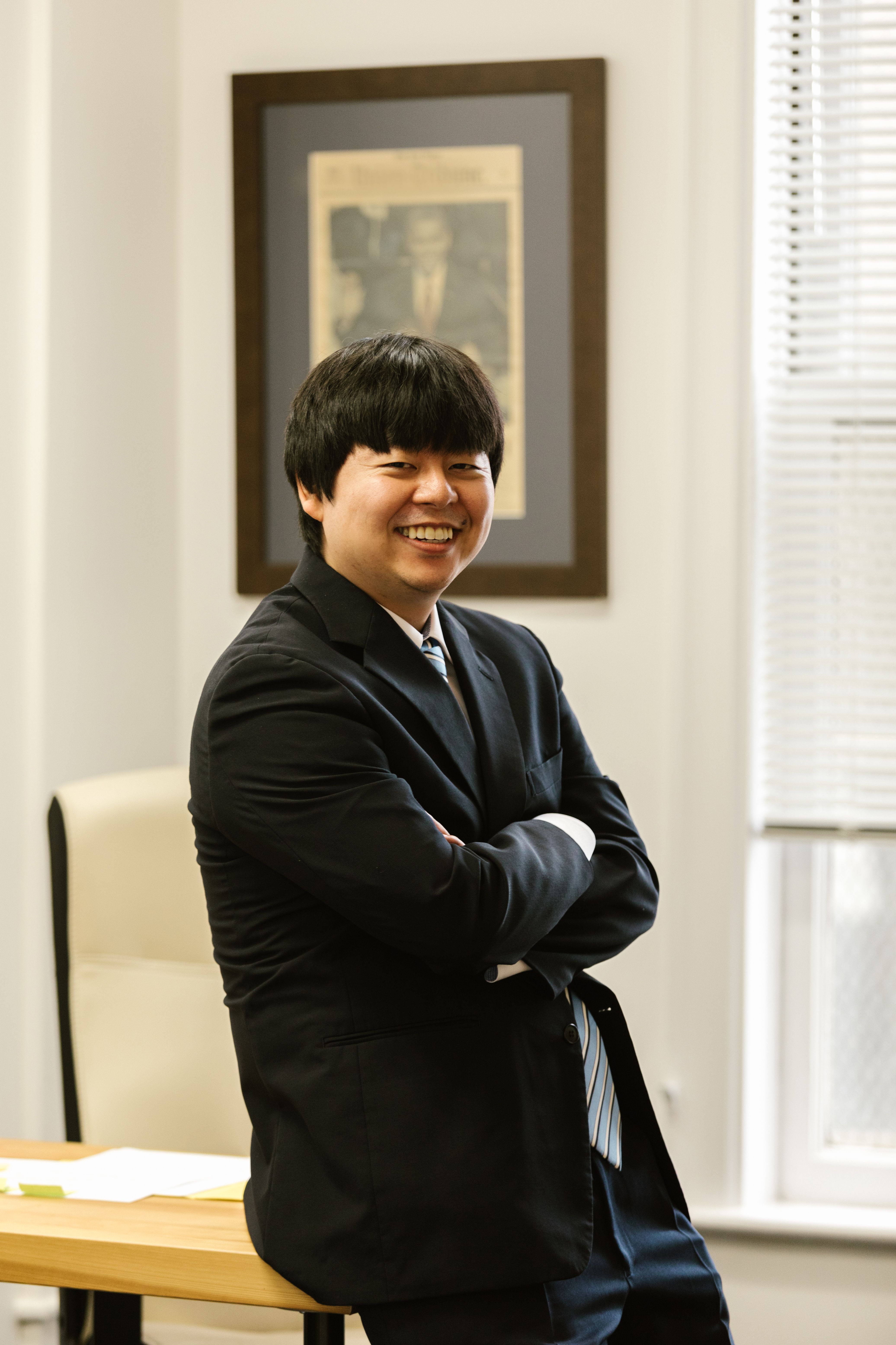 Smiling Asian businessman in a black suit.