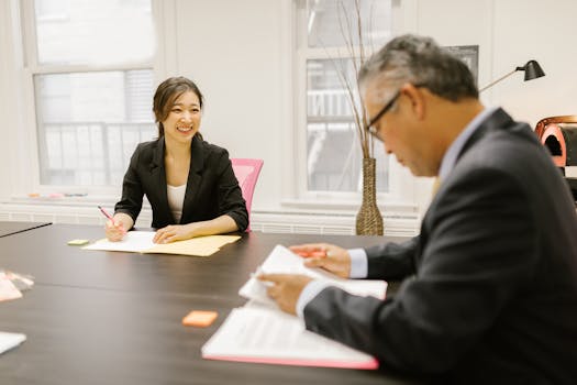 Smiling colleagues in corporate attire engaged in a business meeting at a modern office.