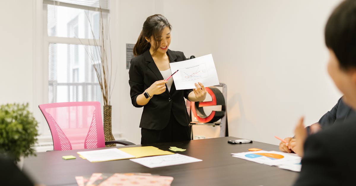 Asian business team in a meeting, presenting charts and discussing strategies in a modern workspace.