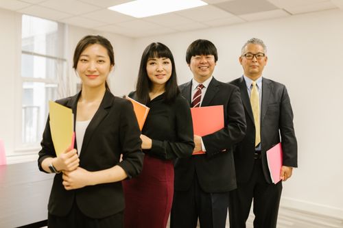 Free A diverse group of professionals posing confidently in a modern office setting with folders. Stock Photo