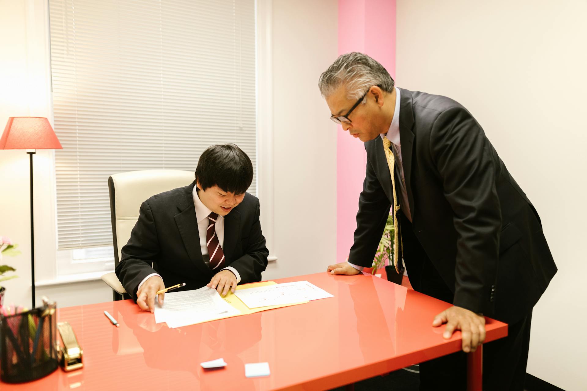 Two businessmen discussing paperwork in a modern office environment.