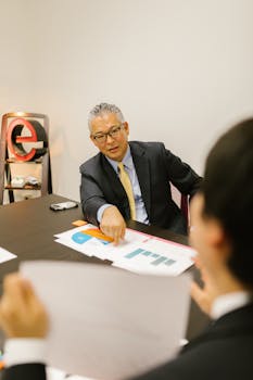 Mature businessman in corporate attire reviews documents with colleagues in an office setting.
