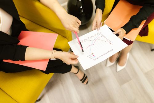Free Two businesswomen in a meeting analyzing charts and graphs in an office setting. Stock Photo