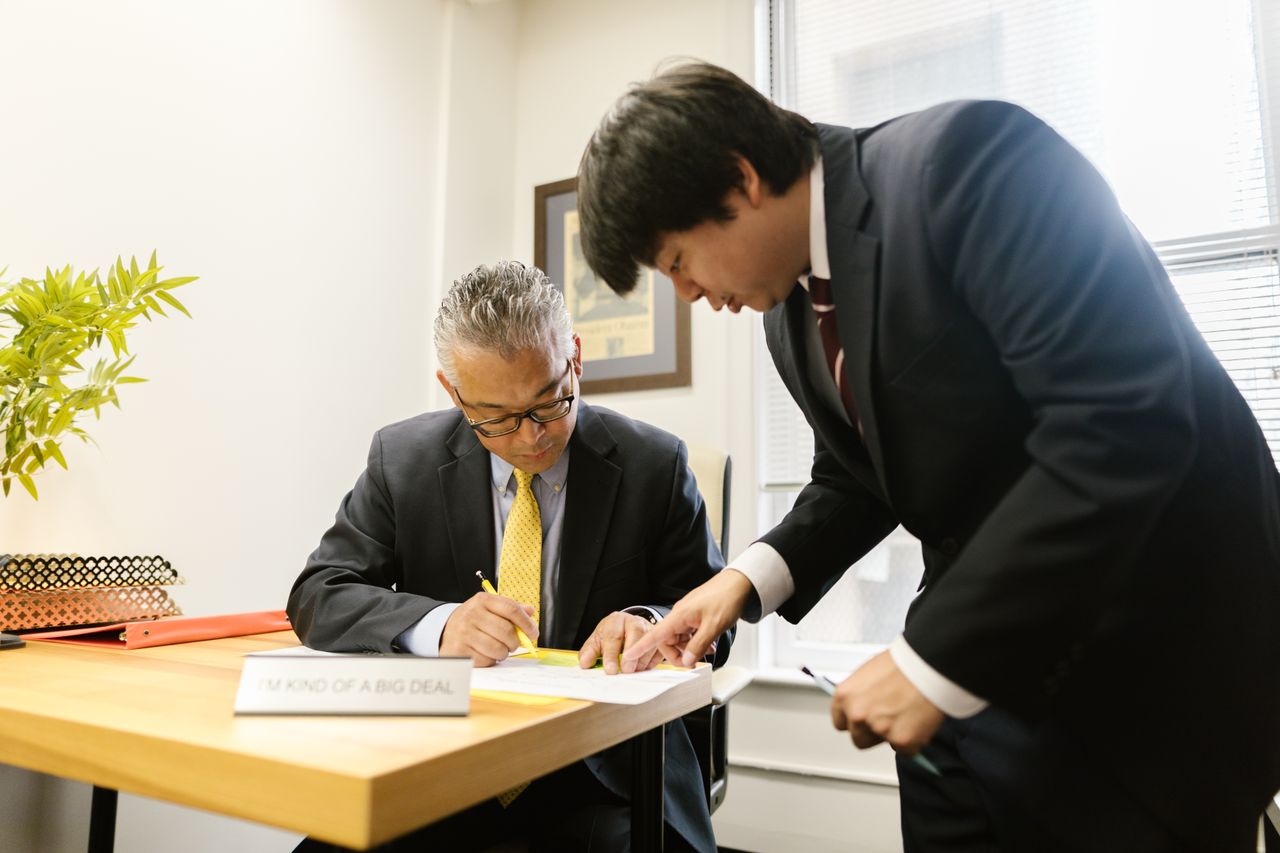 後継者に書類を引き継ぐ経営者