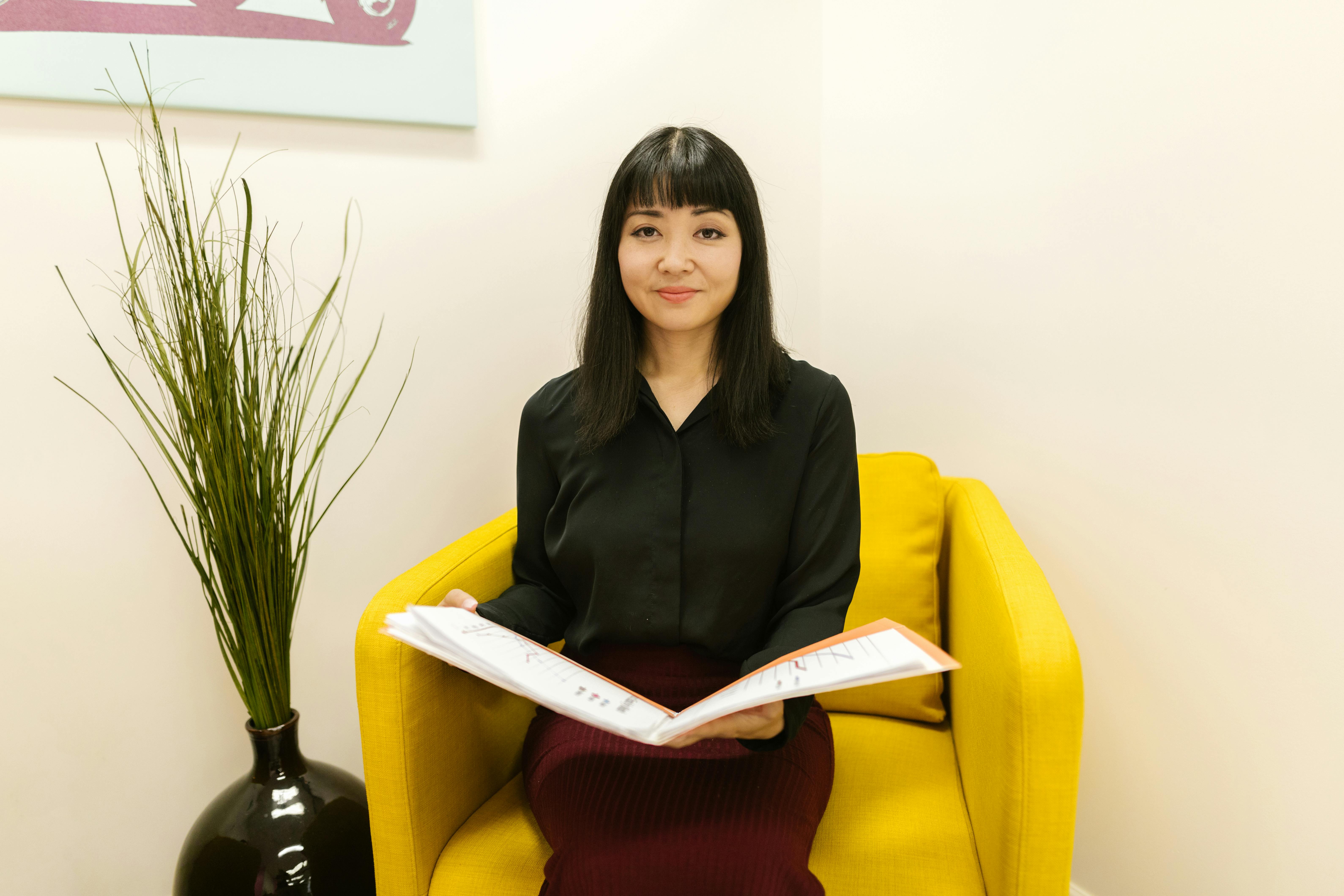 a woman holding charts while sitting on a yellow chair