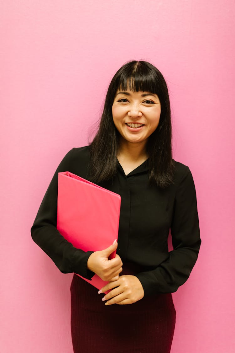 
A Woman Wearing A Black Outfit Holding A Binder