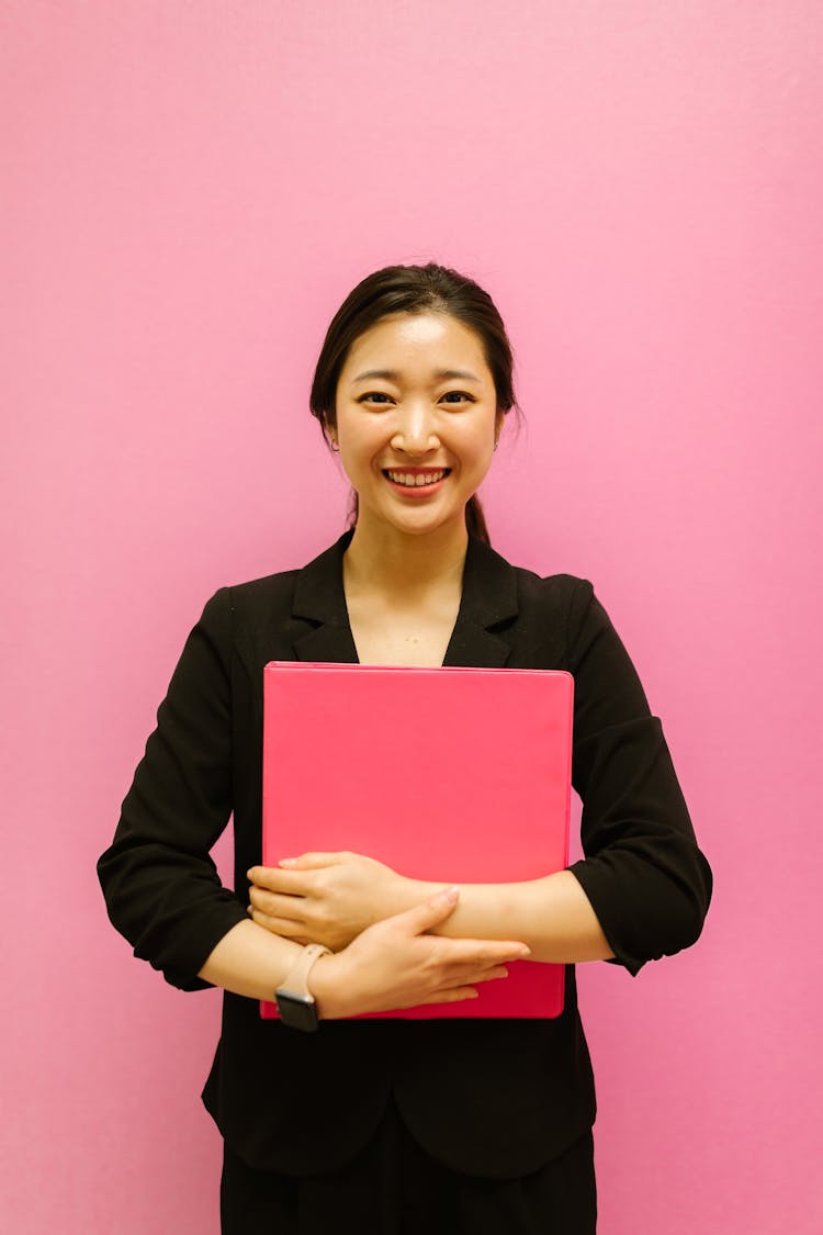 A Woman Wearing A Blazer Holding A Binder