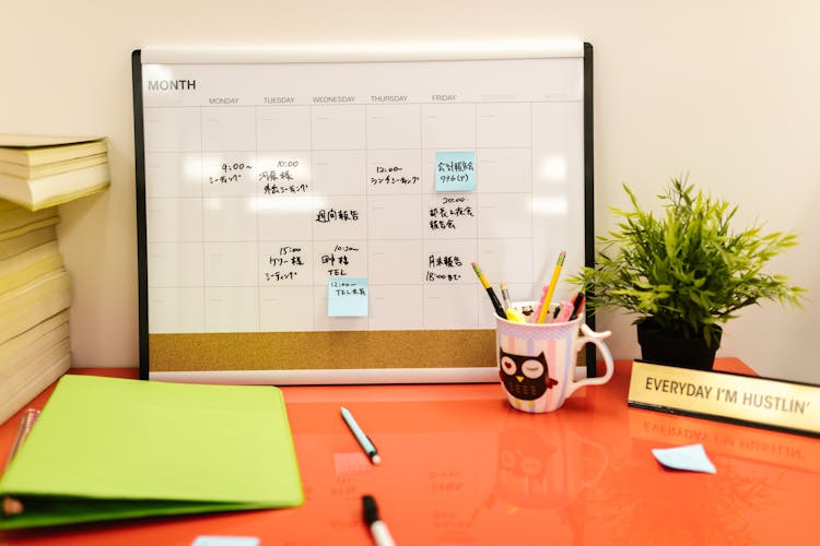 A Desk Calendar With Notes And Post Its On Orange Desk