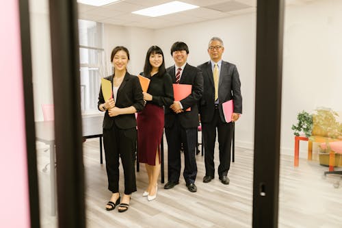 Free Men and Women Standing in Room Holding Folders Stock Photo