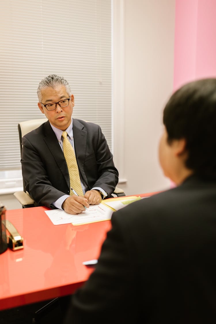 Man In Black Suit Talking To A Person 