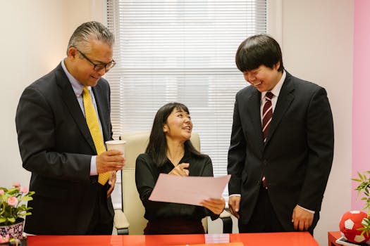 Three professionals collaborate in a modern office setting, discussing documents with smiles.