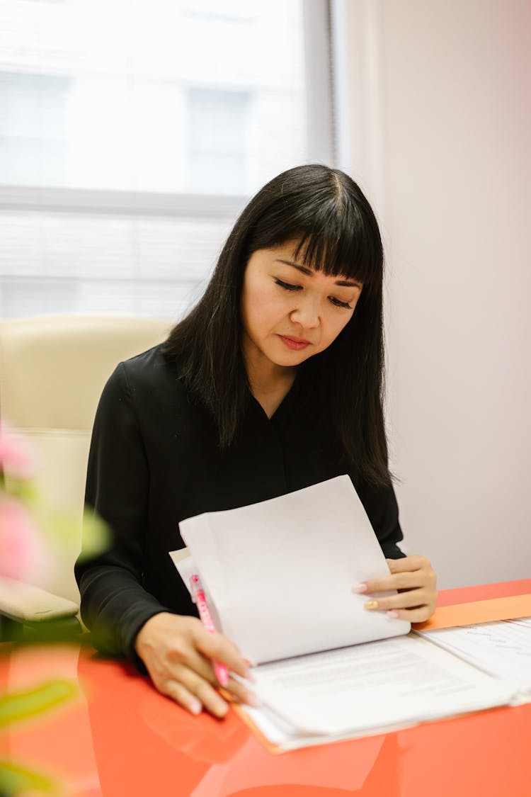 Woman Sitting At Table Looking At Documents