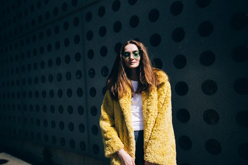 Free Stylish woman in yellow fur coat and sunglasses posing outdoors. Stock Photo