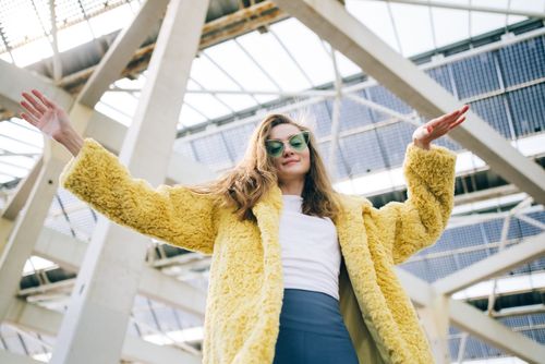 Free Stylish woman standing outdoors in a yellow fur coat and sunglasses. Stock Photo