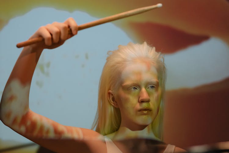 A Woman In White Tank Top Holding A Drumstick