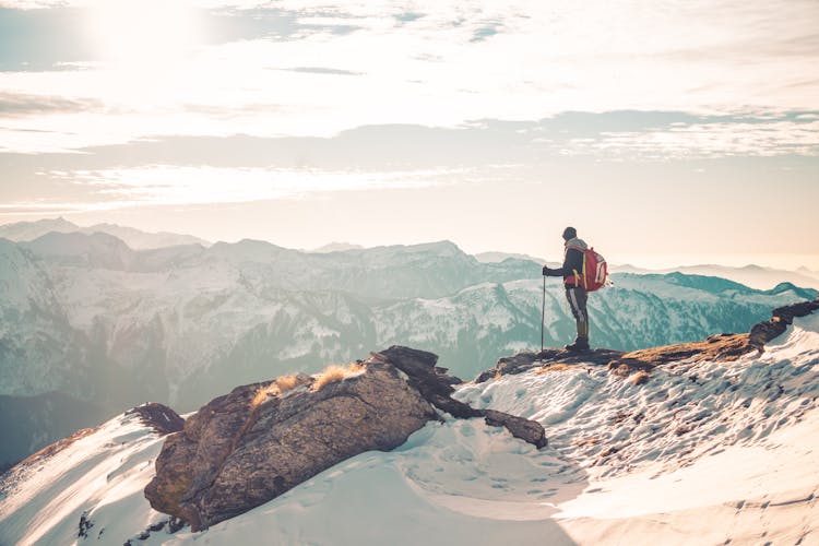 Person Standing On Top Of Snow Covered Mountain