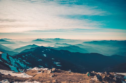 Free Captivating view of a mountain range stretching beneath a serene blue sky with clouds. Stock Photo