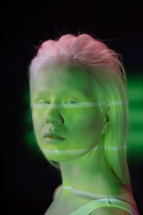 Free Conceptual portrait of a young woman in studio with artistic neon lighting. Stock Photo