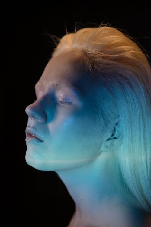 Free Close-up portrait of a woman with blue and yellow lighting on her fair complexion. Stock Photo