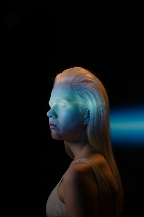 Free A striking portrait of a young woman with vibrant lighting effects and a dark background. Stock Photo