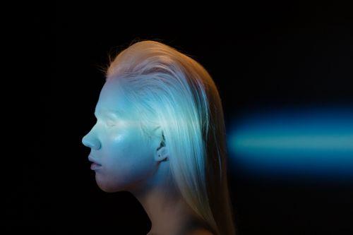 Free Artistic side profile of a woman with blue light projection on a dark background. Stock Photo