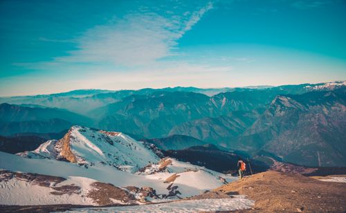 Free Scenic view of a winter mountain landscape with a solitary hiker under blue skies. Stock Photo