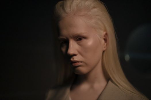 Artistic portrait of an albino woman with selective focus in a dark studio setting.