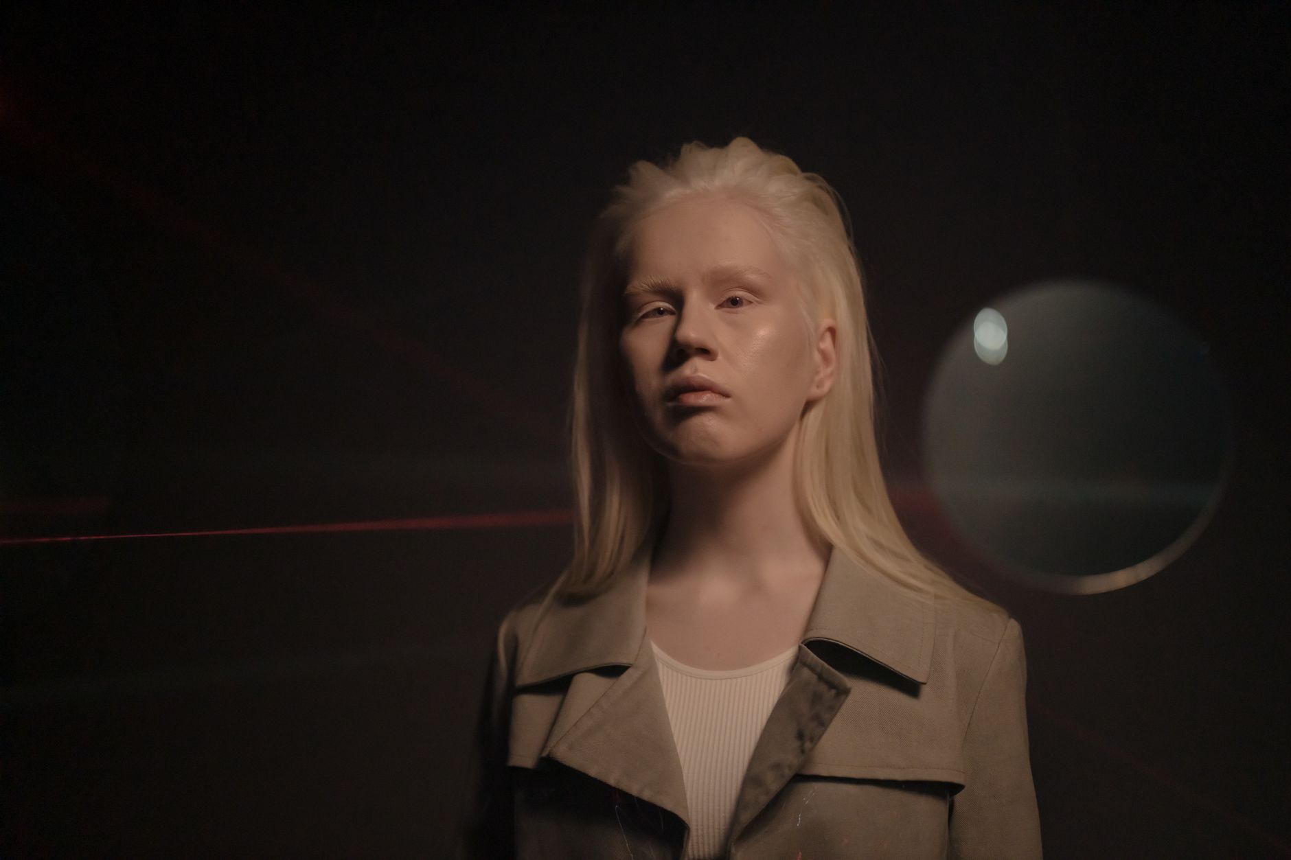 Studio portrait of an albino woman with thoughtful expression in soft lighting.